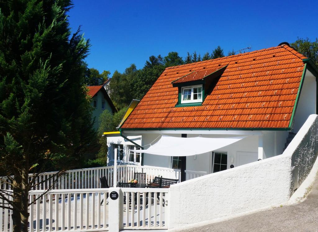 uma casa branca com um telhado laranja e uma cerca branca em Ferienhaus BLACK & WHITE em Bromberg