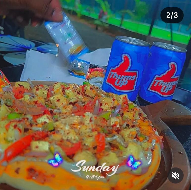 une pizza sur une table avec deux canettes de soda dans l'établissement Amigos, à Annavaram