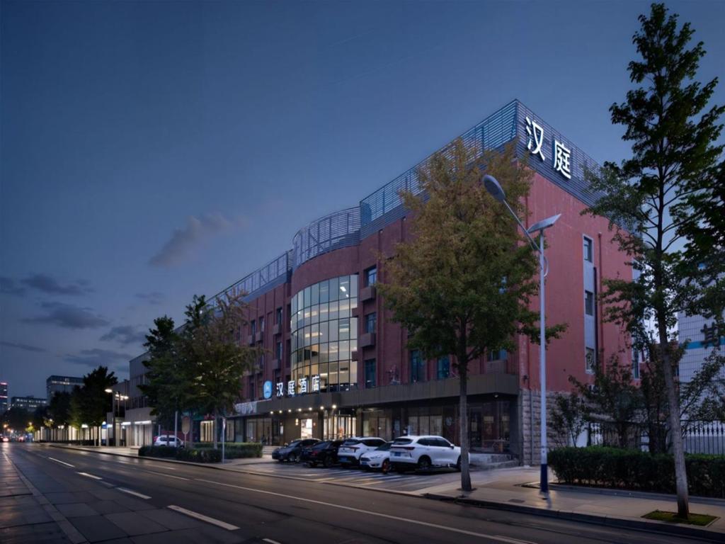 ein Gebäude mit Autos, die davor auf einer Straße geparkt sind in der Unterkunft Hanting Hotel Beijing Daxing New Town Jinxing Bridge in Peking