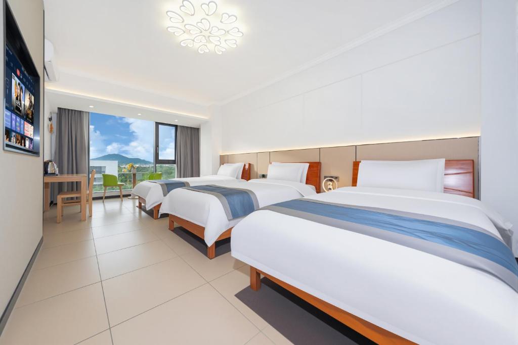 a hotel room with three beds and a table at UHotelPhoenixInternationalAirport in Sanya