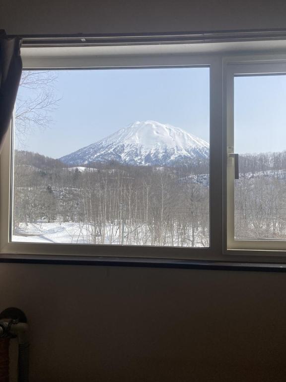 ein Blick auf einen schneebedeckten Berg durch ein Fenster in der Unterkunft Cottage Akagera in Wada