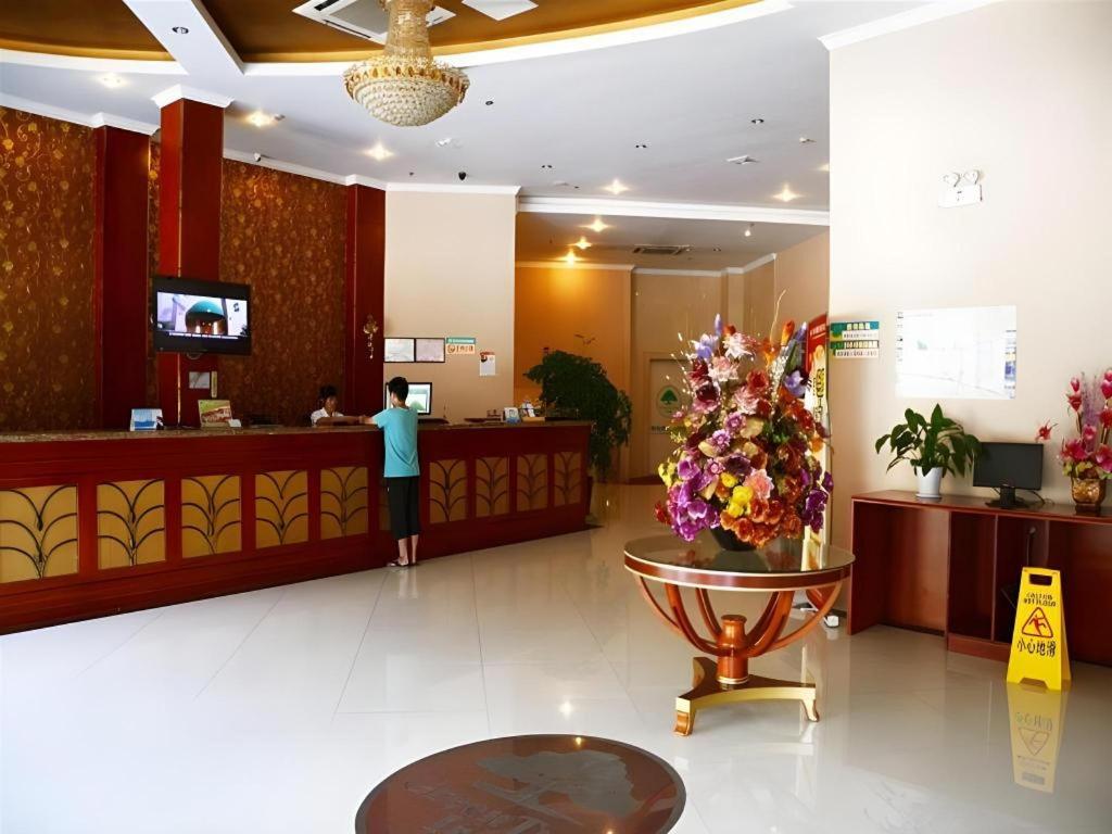 un homme debout au comptoir d'un hall d'hôtel dans l'établissement GreenTree Inn Kunshan Shimao Plaza Business Hotel, à Penglang