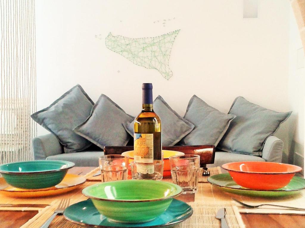 a table with a bottle of wine and bowls on it at Casa Maier in Trapani