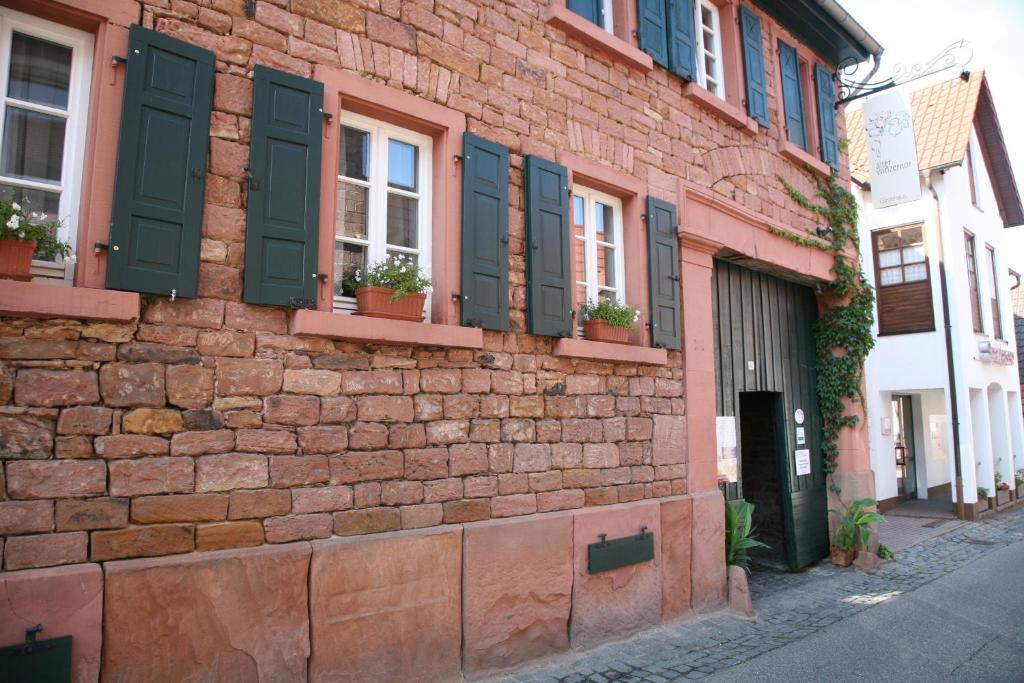 a brick building with green shutters on a street at Alter Winzerhof Weisenheim am Berg e.K. in Weisenheim am Berg