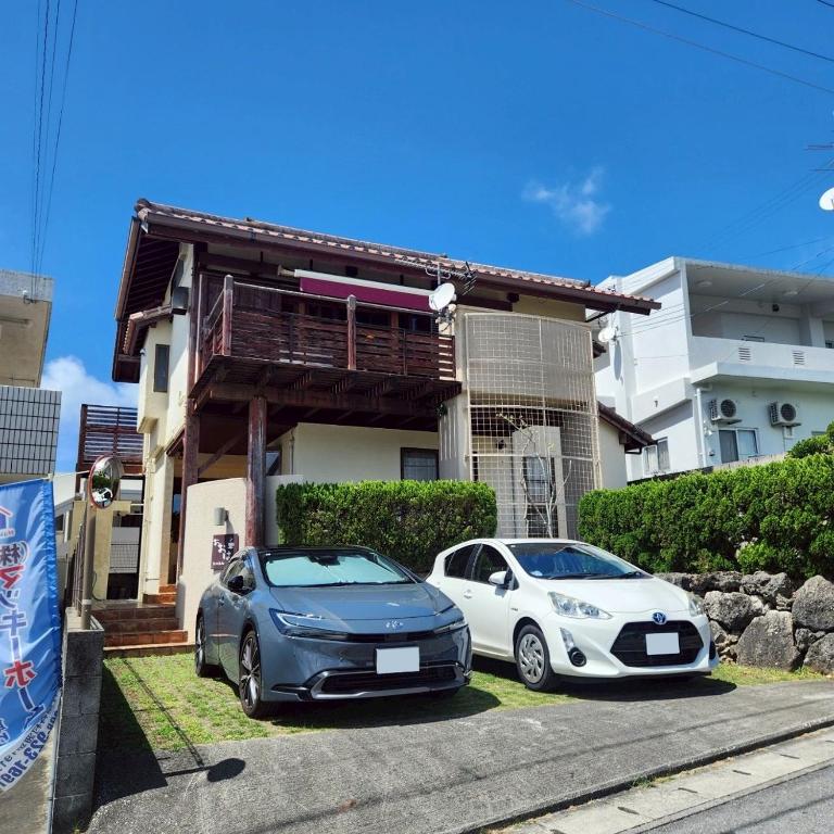 two cars parked in front of a house at お休み処おおはま in Yomitan
