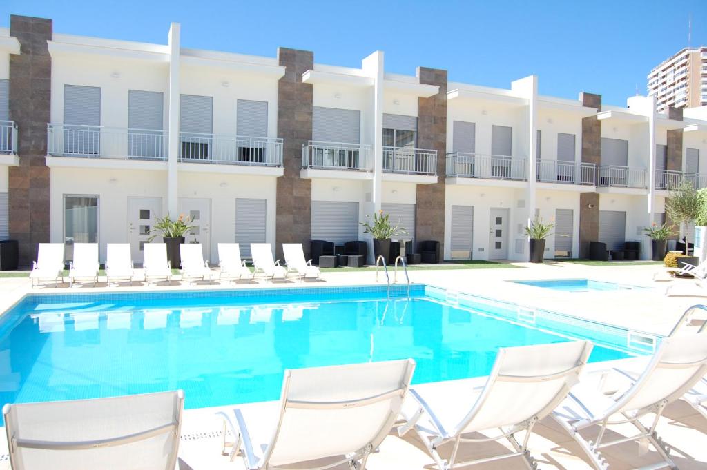 una piscina con sillas y un edificio en Villas Mare Residence, en Nazaré