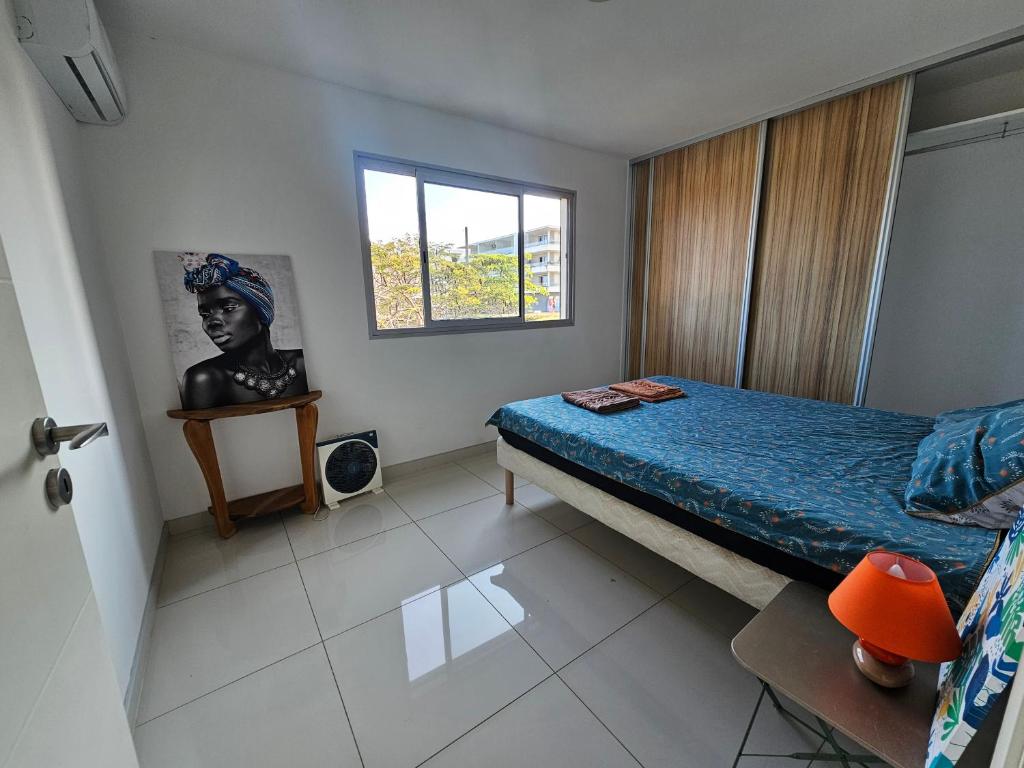 a small bedroom with a bed and a window at F3 entier de standing tout équipé vue mer, piscine partagée et parking souterrain in Noumea