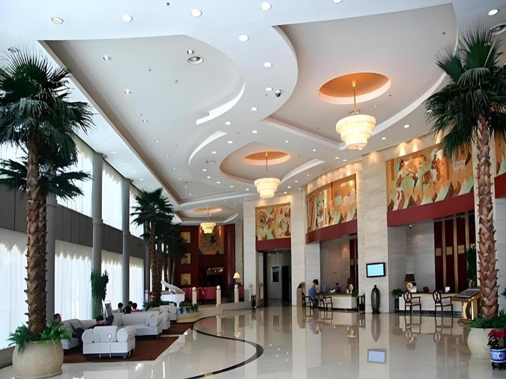 eine Lobby mit Palmen in einem Gebäude in der Unterkunft Dunhuang Grand Soluxe Hotel in Dunhuang