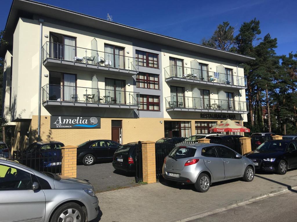 a building with cars parked in front of it at Villa Amelia in Niechorze