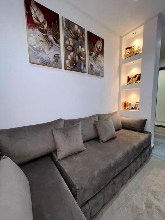 a couch in a living room with three pictures on the wall at Sidi ifni hébergement in Sidi Ifni