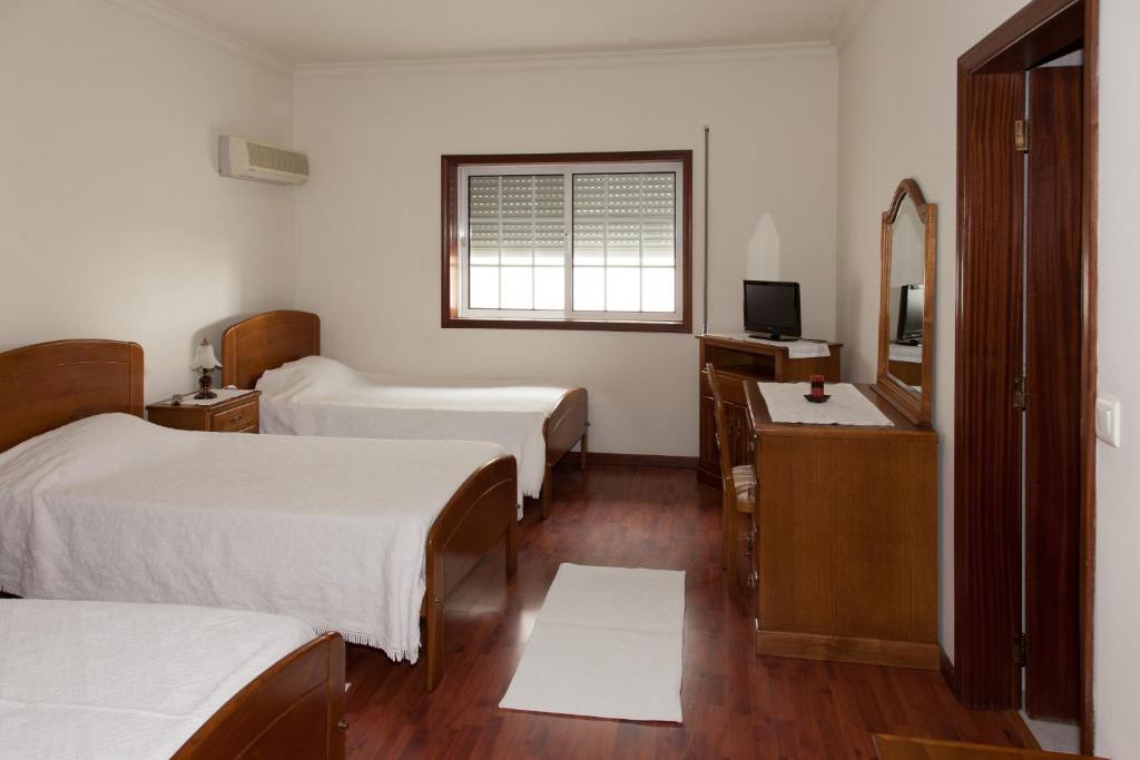 Habitación de hotel con 2 camas y espejo en Residencial O TRINDADE, en Águeda