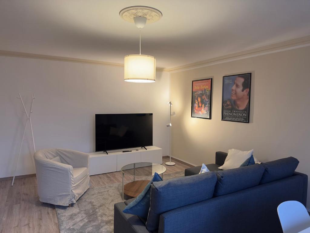 ein Wohnzimmer mit einem blauen Sofa und einem Fernseher in der Unterkunft PanoramaOase - stilvoll & ruhig - 75qm in Halle an der Saale