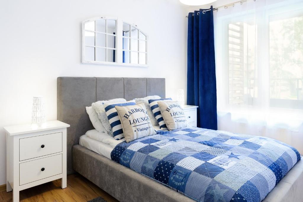 een bed met een blauwe en witte plaid deken bij Apartament Mare Deluxe Polanki in Kołobrzeg