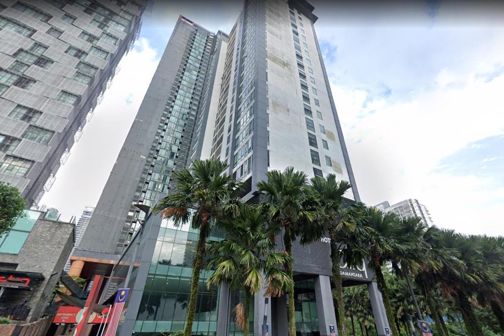 Un edificio alto con palmeras delante. en NapzBox, en Petaling Jaya