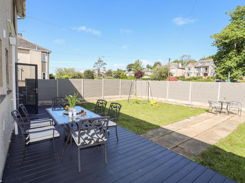 a patio with a table and chairs on a deck at Glan Aber in Pwllheli