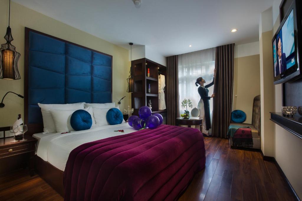 um quarto com uma cama grande com balões e uma mulher a olhar pela janela em Ambassador Hanoi Hotel & Travel em Hanói