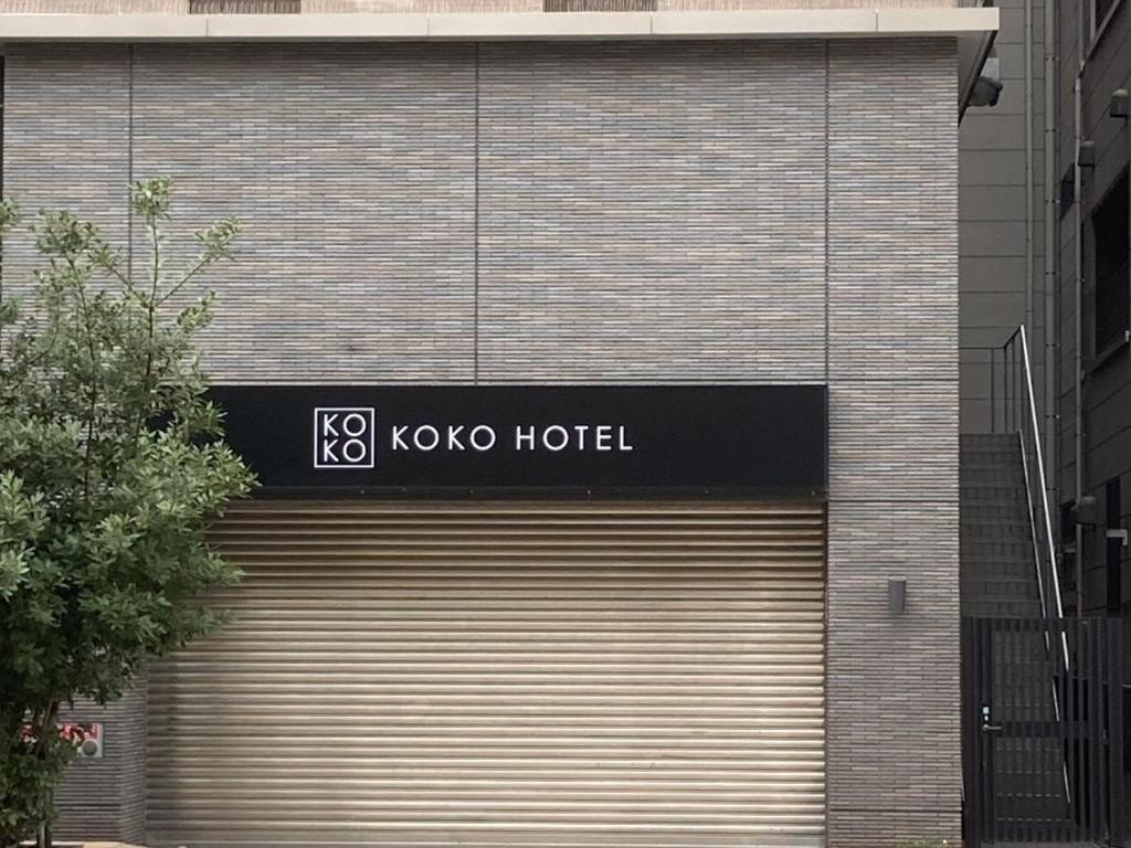 a koxo hotel building with a closed garage door at KOKO HOTEL Kobe Shinnagata - formerly Hotel Wing International Kobe - Shinnagata Ekimae in Kobe