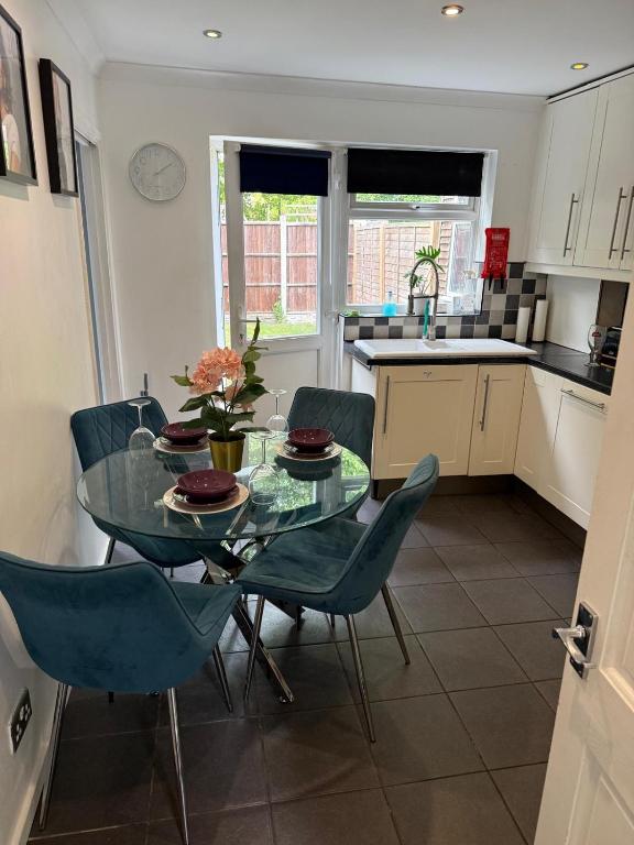 a kitchen with a glass table and blue chairs at Flamingo Short Lets Greenleys in Wolverton