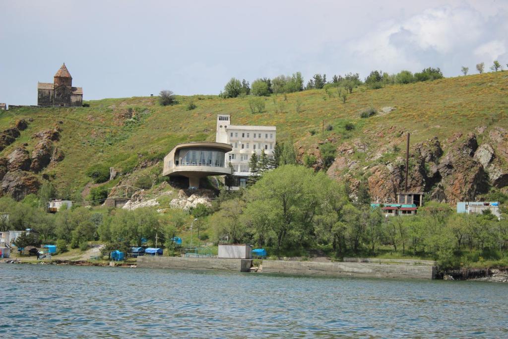 una casa en una colina junto a un cuerpo de agua en Sevan Writers House en Sevan