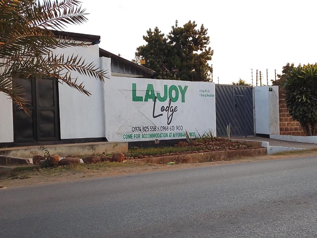 ein Gebäude mit einem großen Schild an der Straßenseite in der Unterkunft Lajoy Executive Lodge in Lusaka