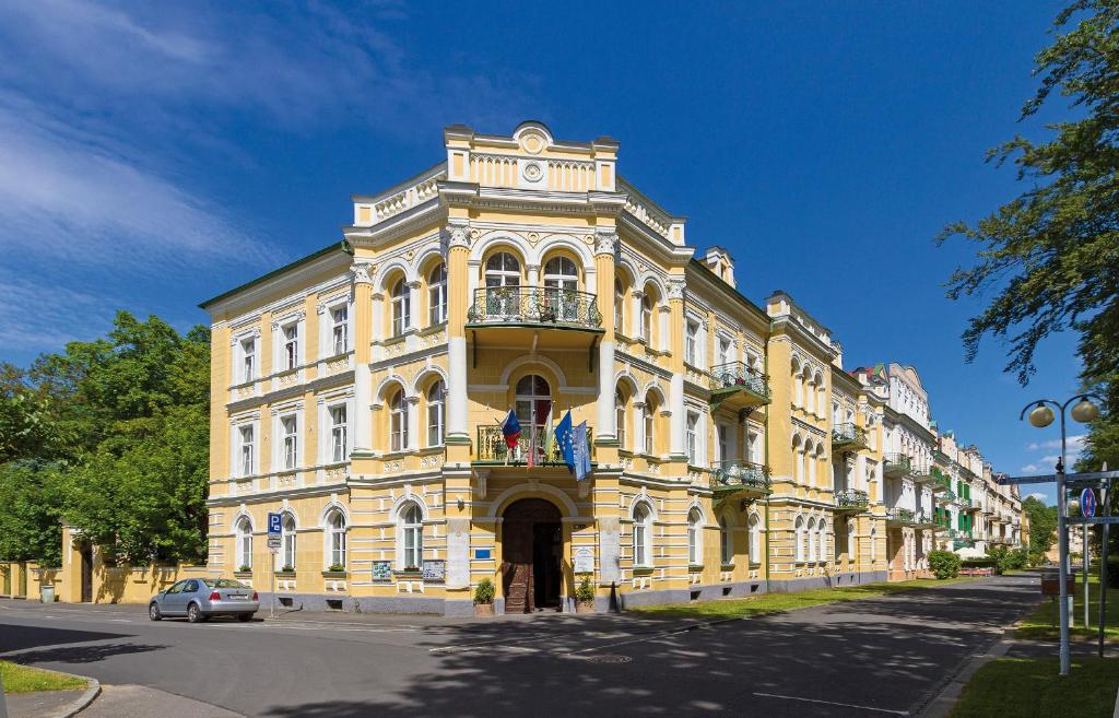 a large yellow building with a balcony on a street at Hotel Metropol in Františkovy Lázně