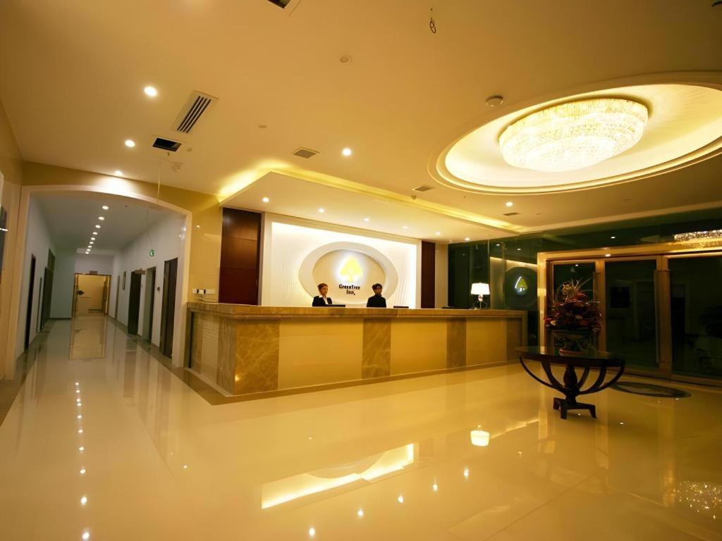 a lobby of a hotel with two people sitting at a counter at GreenTree Inn JinDeZhen People Square Taoxichuan Wenchuang Street in Jingdezhen
