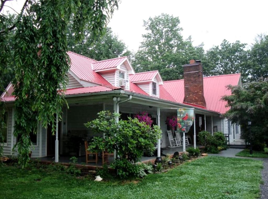 Blue Ridge Manor Bed and Breakfast في Fancy Gap: منزل بسقف احمر وساحة