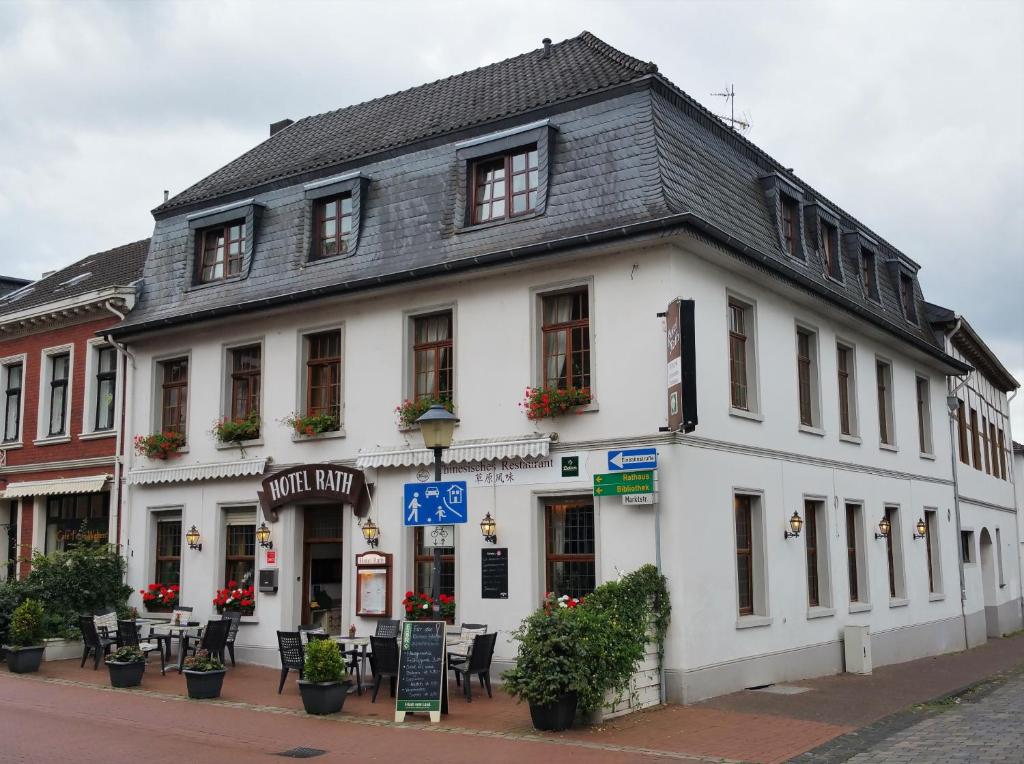 a white building with a black roof on a street at Hotel Rath in Schwalmtal