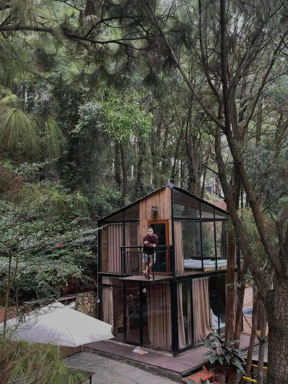 a man standing on the balcony of a tree house at DeBay Retreat - Little Đà Lạt Chill Villa in Sóc Sơn