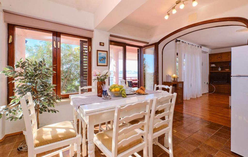 uma cozinha e sala de jantar com uma mesa e cadeiras brancas em Melone Apartman 3 Senj by Villas Guide em Sveti Juraj