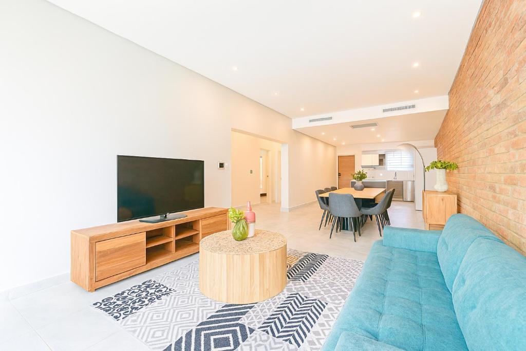a living room with a blue couch and a tv at Iconyc Apartment in Brentwood Park