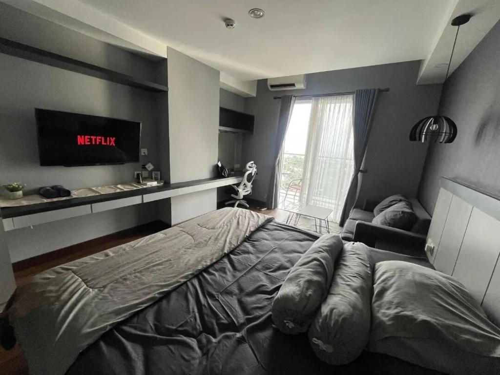 a bedroom with a bed and a tv on the wall at The Haven Room at Mataram City Apartment - Yudhistira Tower in Kejayan