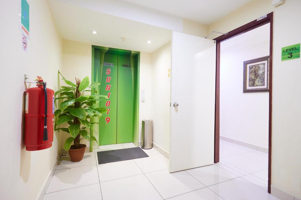 A bright third-floor landing has a green hotel-branded lift, framed artwork and a potted plant.