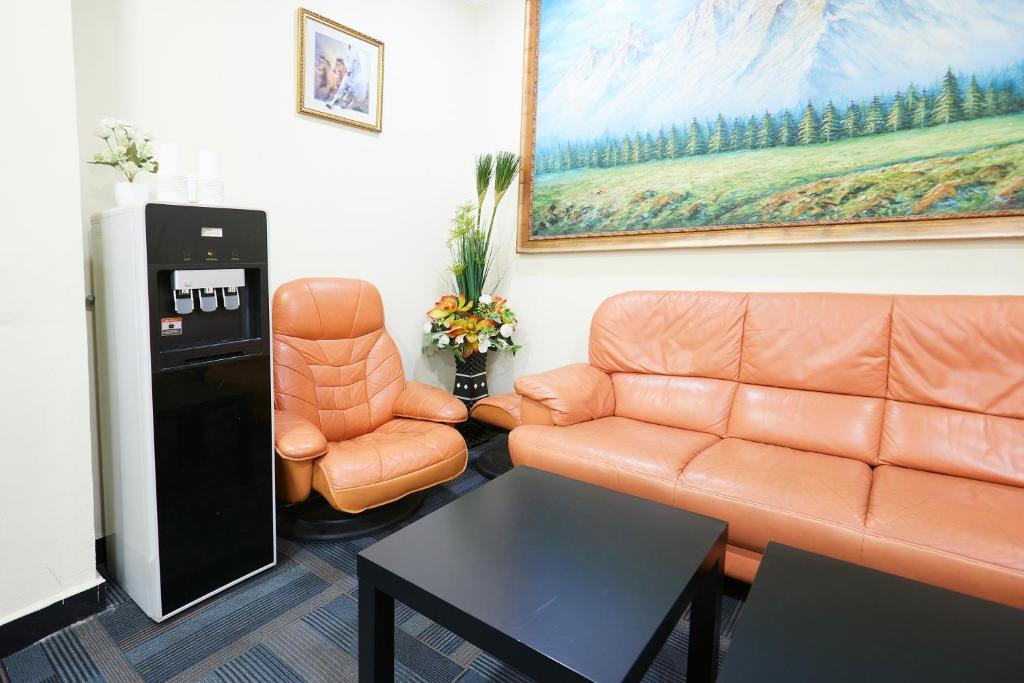 A furnished lounge offers a leather sofa, armchairs, coffee tables and a drinks dispenser.