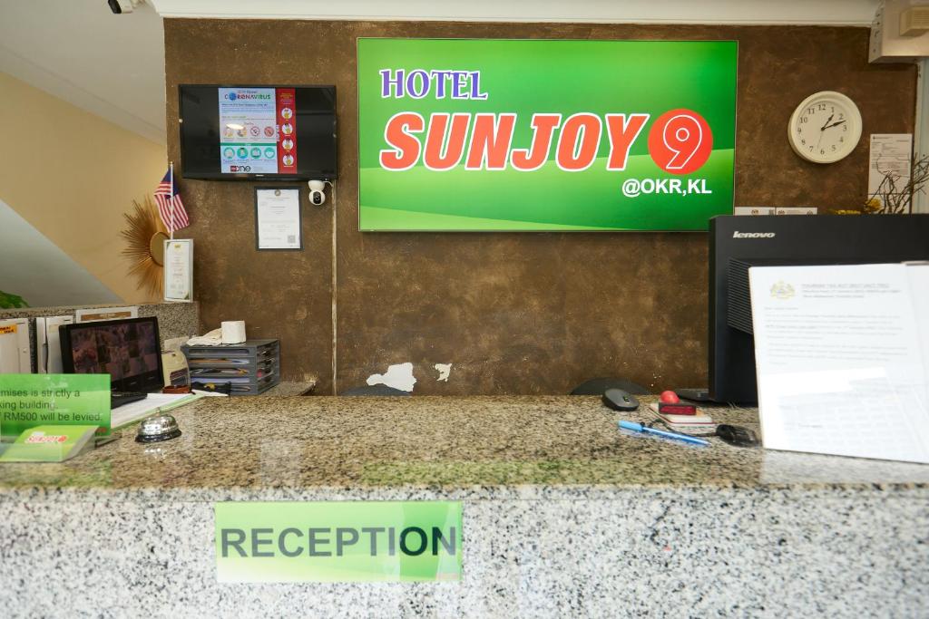 A compact reception desk with the hotel’s illuminated branding behind it.