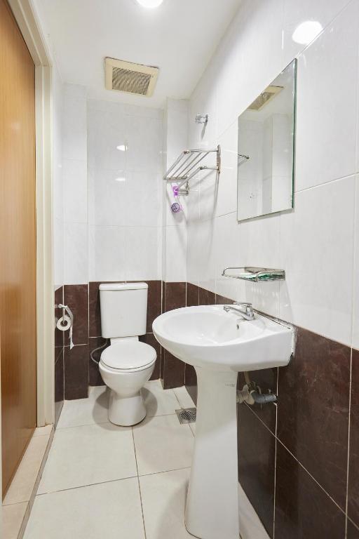 A compact bathroom with a pedestal sink, toilet and open shower area.