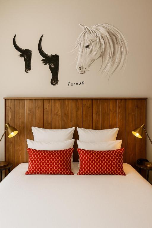 a bed with two red pillows and a horse on the wall at Hotel Saint Louis - Au Coeur des Remparts in Aigues-Mortes