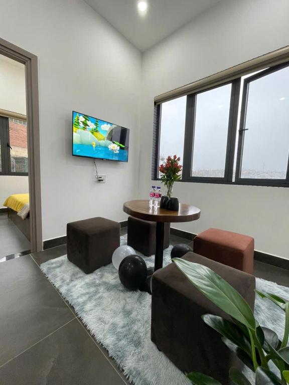 a living room with a table and a tv on a wall at Căn hộ Đà Lạt Cảnh in Da Lat