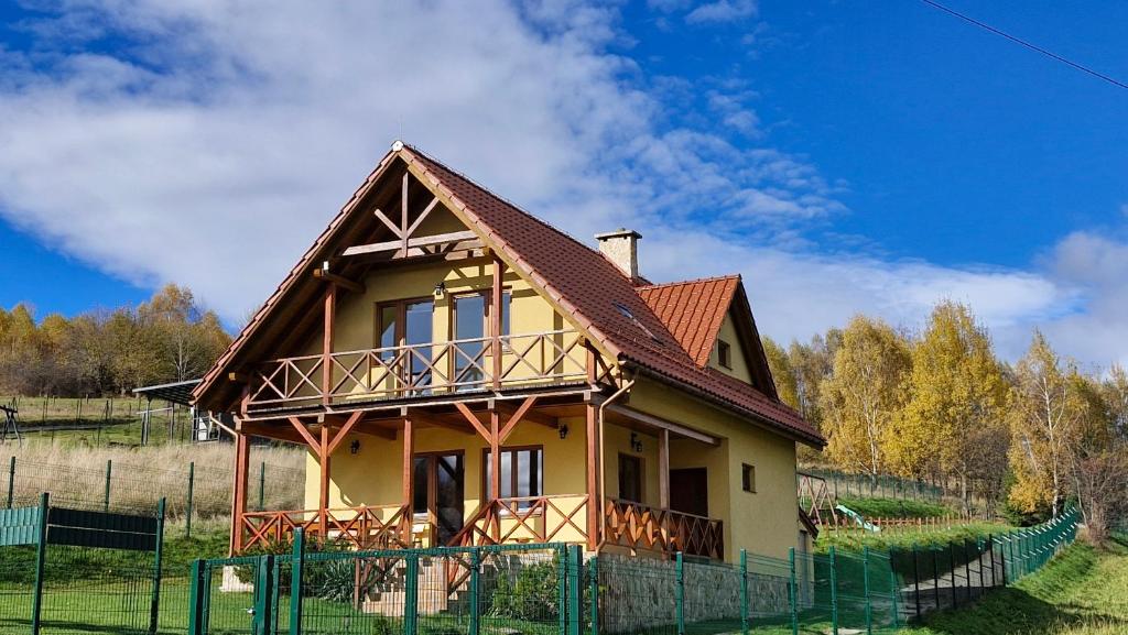 a house with a brown roof on a field at Domek Wichrowy groń in Korbielów