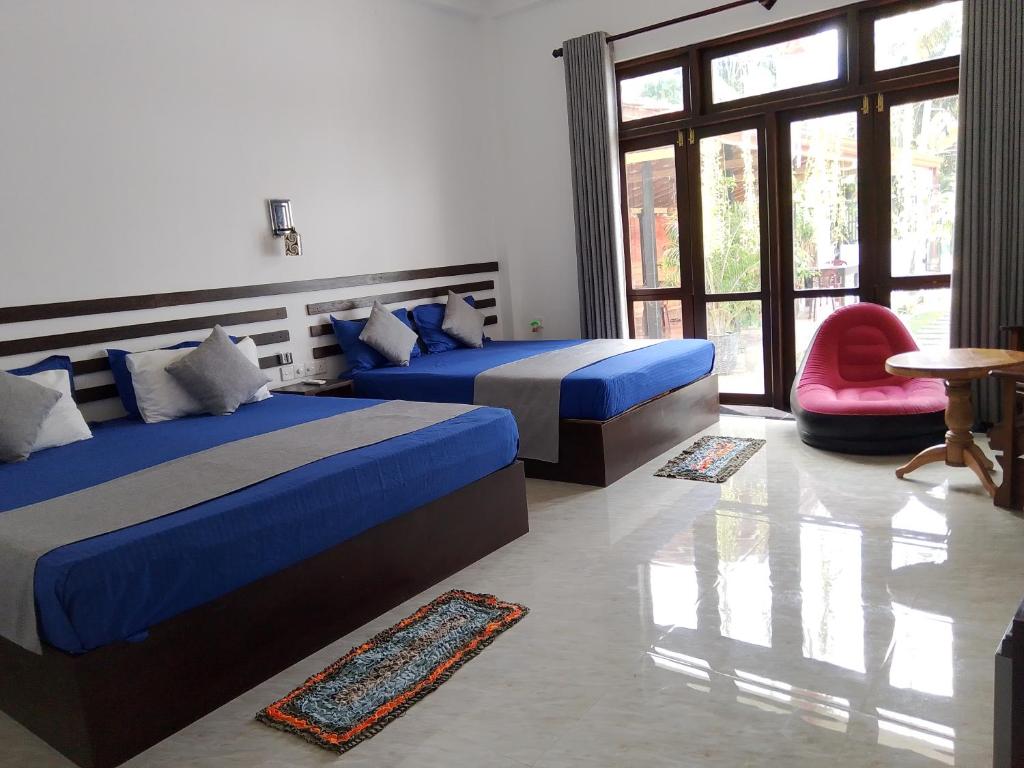 1 Schlafzimmer mit 2 Betten und einem roten Stuhl in der Unterkunft Indunil Family Residence With Pool Hiriketiya in Dikwella