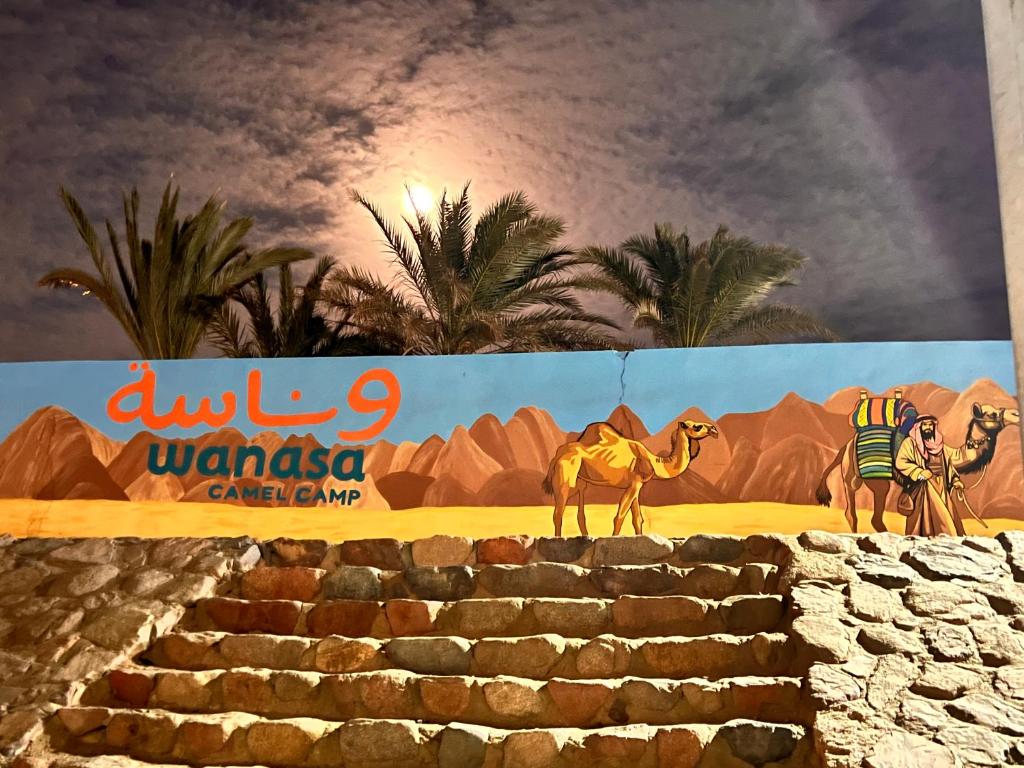 a mural of a camel and a sign in the desert at Wanasa Camel in Dahab