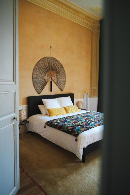 a bedroom with a large bed with a fan on the wall at Le Henri II - 15 min du circuit, arrivées & départs autonomes in Le Mans