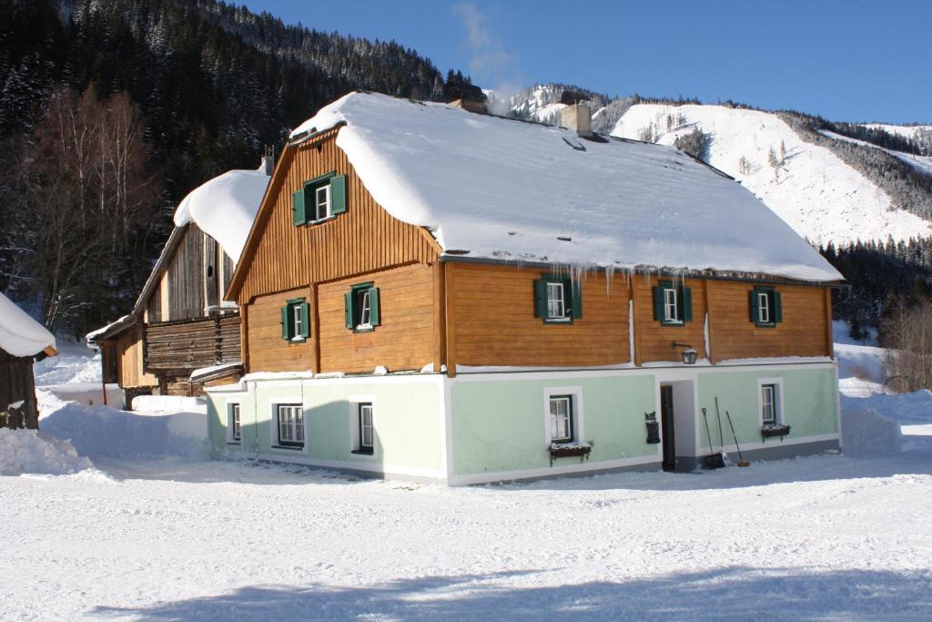 ein großes Holzhaus mit Schnee auf dem Dach in der Unterkunft Ferienwohnung Schaupphof in Donnersbachwald