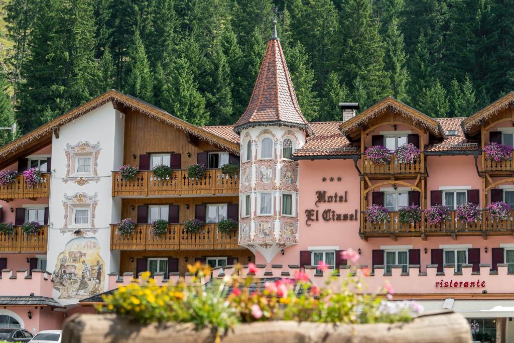 ein großes rosafarbenes Gebäude mit Balkonen und Blumen in der Unterkunft EL CIASEL in Canazei