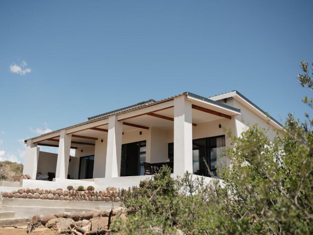 a white house with columns at Bergendam Eco Lodge in Venterstad