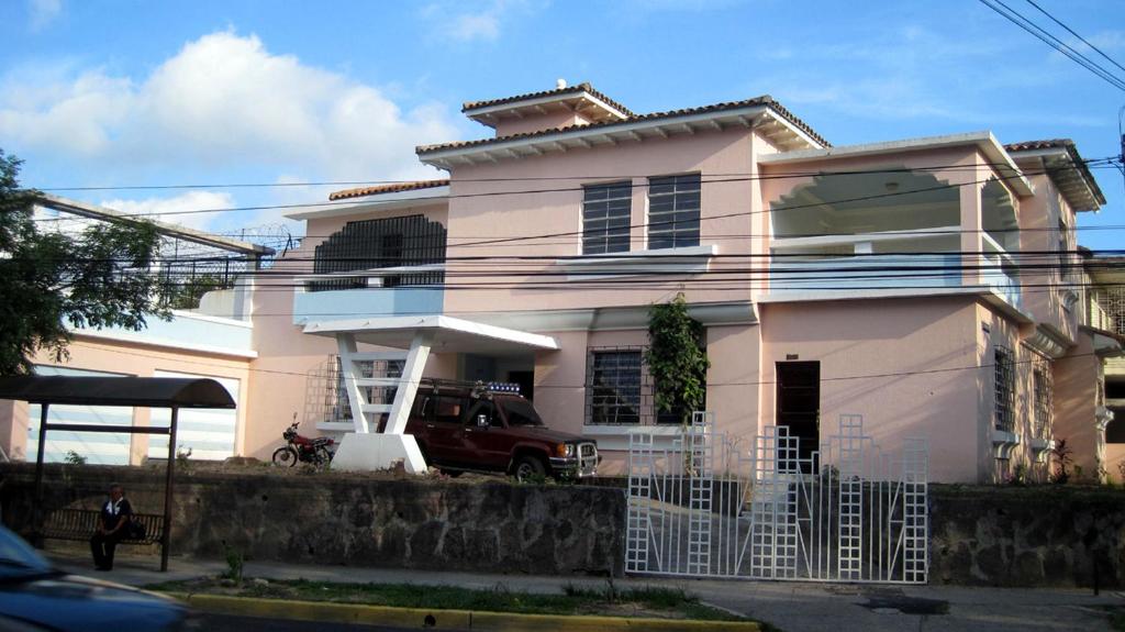 una casa blanca con una furgoneta estacionada frente a ella en Hostal Cumbres del Volcan Flor Blanca en San Salvador