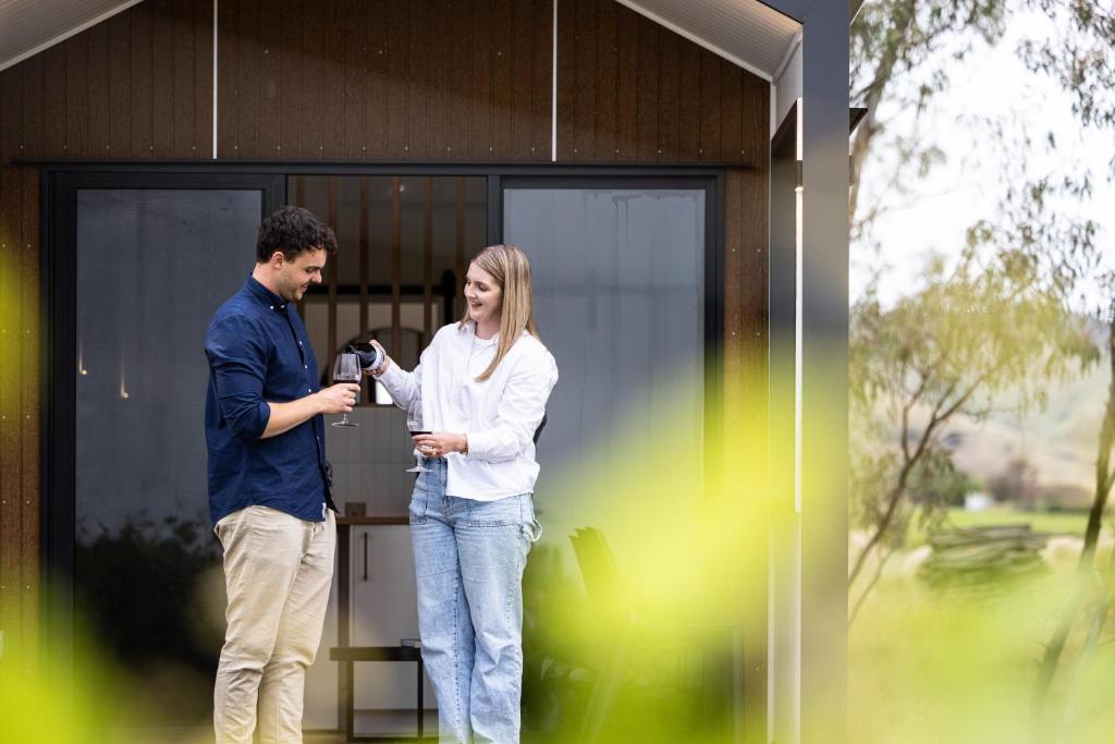 Ein Mann und eine Frau stehen vor einem Haus. in der Unterkunft Seabrook Vineyard Retreat 