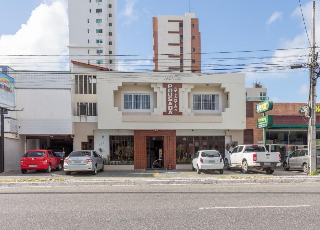 a building with cars parked in a parking lot at Hotel Pousada Atlântica in João Pessoa