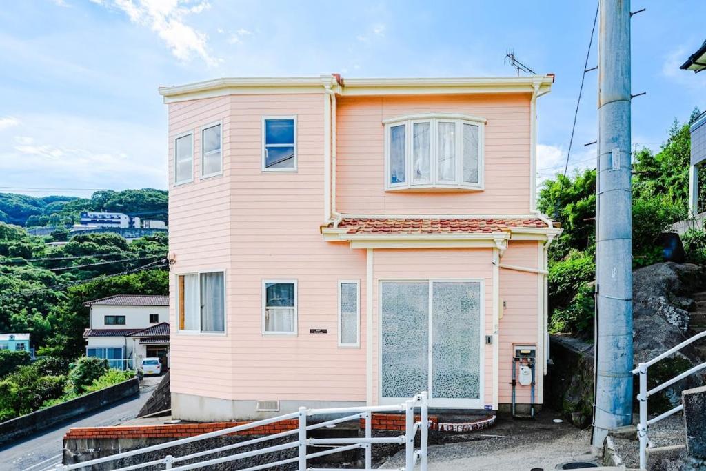 una casa rosa sentada en la cima de una colina en 長崎観光の拠点に最適グラバー園近くの一軒家ステイ, en Nagasaki