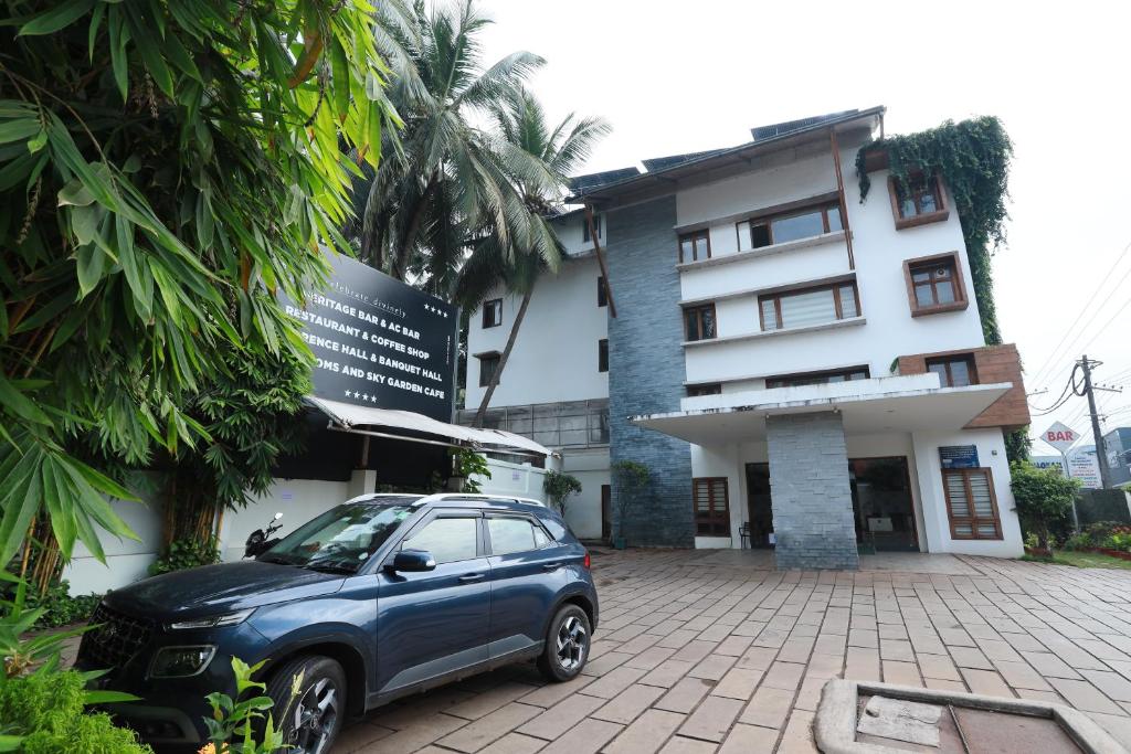 Un coche azul aparcado delante de un edificio en Devalokam Grand, en Edappāl